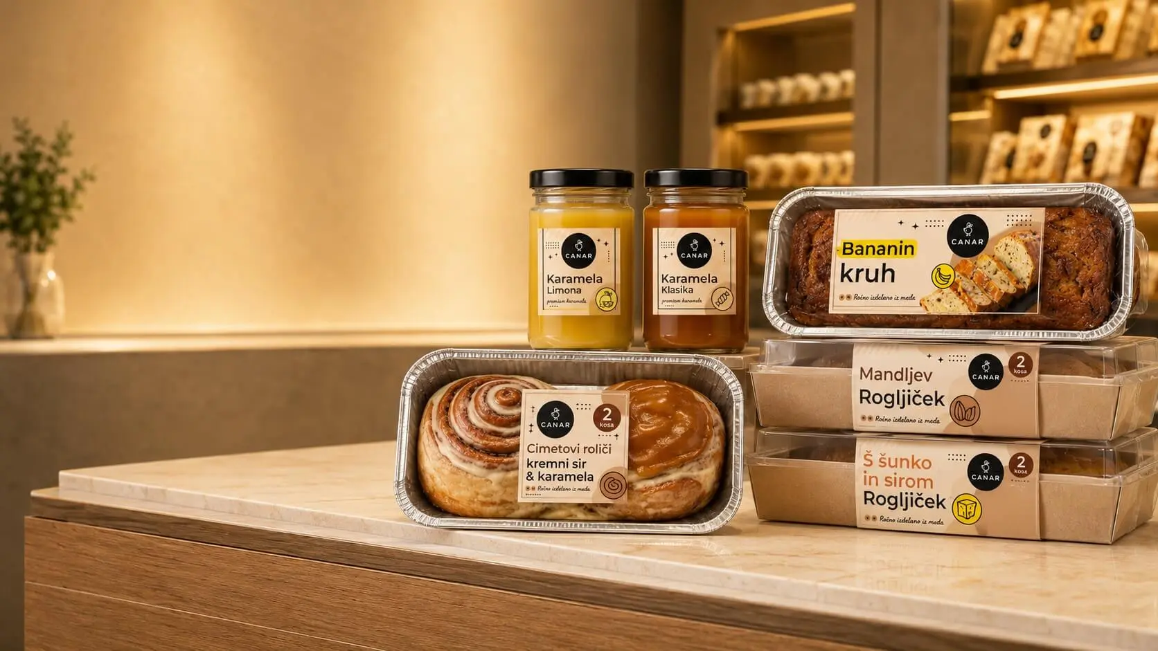 Trgovinska embalaža Canar — bananin kruh, cimetove rolice, mandljev rogljiček, rogljiček s šunko in sirom, karamela.